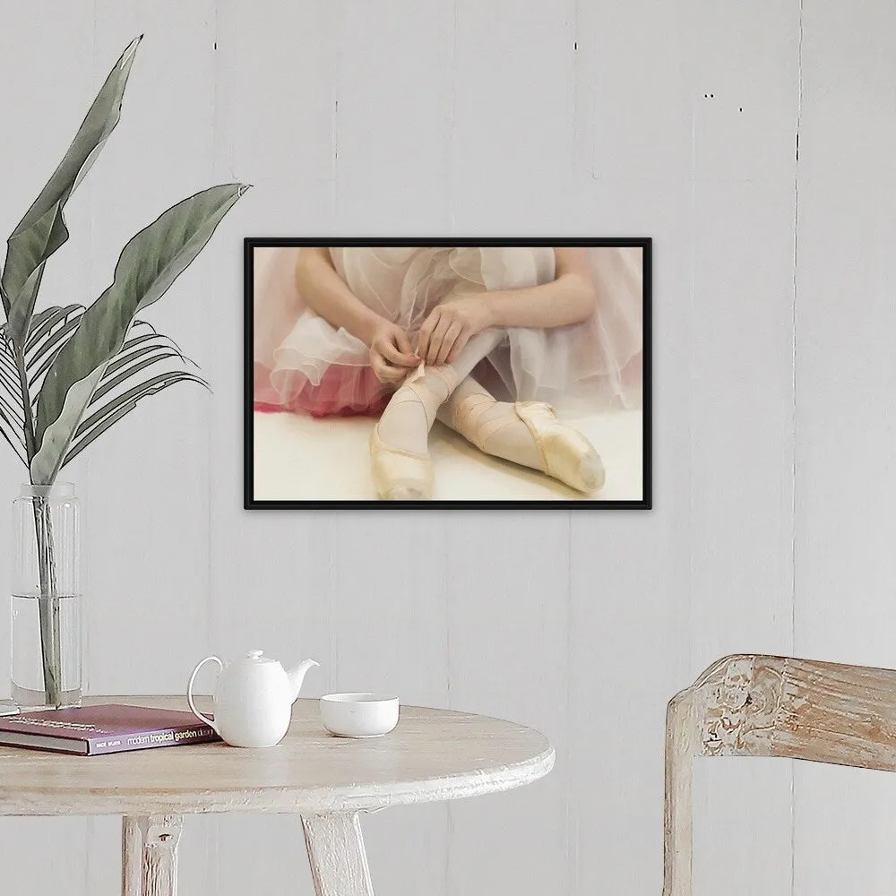 "A ballerina sitting on the floor tying her ballet shoes" Black Float Frame Canvas Art